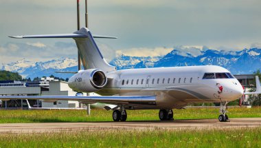 Kloten, İsviçre - 4 Mayıs 2015: arka planda Alplerin zirvelerine Zürih Havaalanı'nda bir Bombardier Global 5000 uçak. Bombardier Global Express büyük bir kabin, Bombardier Aerospace tarafından üretilen ultra uzun menzilli iş jeti mi.