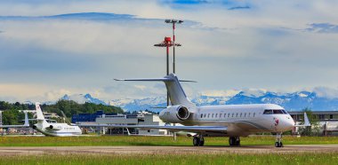 Kloten, İsviçre - 4 Mayıs 2015: görünüm ön plan ve arka planda Alplerin zirvelerine Bombardier Global 5000 uçak ile Zürih Havaalanı'nda. Bombardier Global Express olduğunu büyük kabin, ultra uzun menzilli iş jeti.