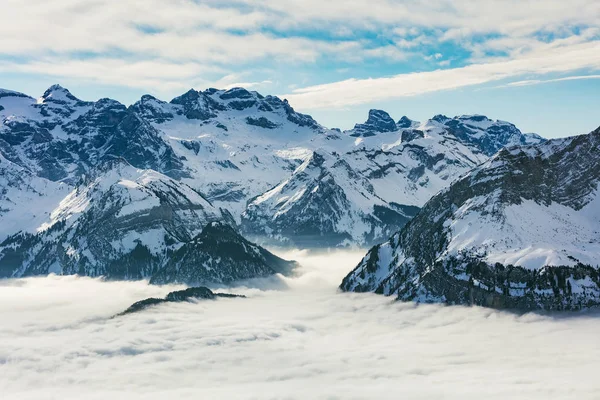Summits of the Alps rising from sea of fog - a wintertime view from the Fronalpstock mountain in the Swiss canton of Schwyz.