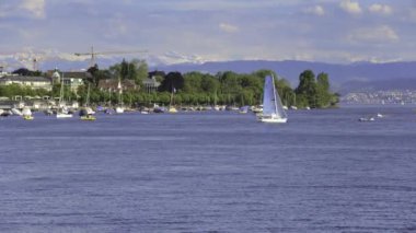 Zürih, Isviçre-31 Mayıs 2019: Zürih Gölü 'ndeki teknelerde insanlar, arka planda Alpler 'in zirveleri-Zürih kentinden görünüm. Zürih Gölü Zürih şehir güneydoğusunda uzanan, Isviçre 'de bir göl.