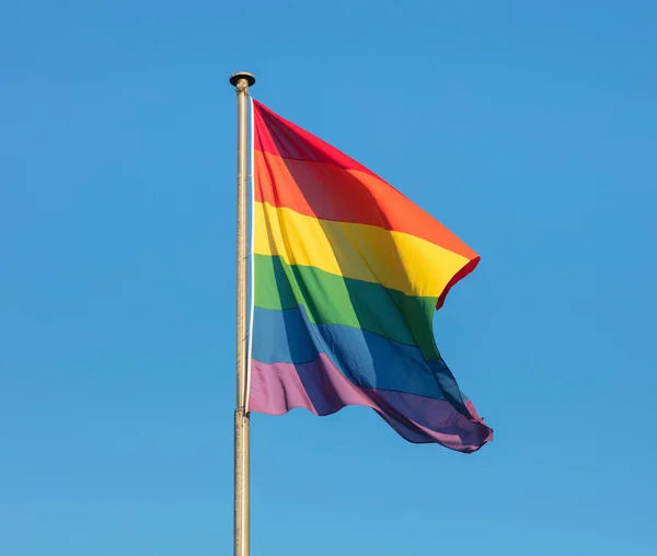 Bandera arco iris del movimiento LGBT contra el cielo azul Imagen de archivo