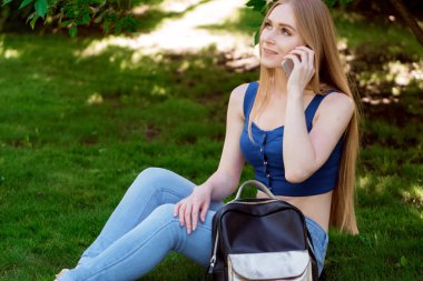 kız telefonu ve çimenlerin üzerine oturmuş