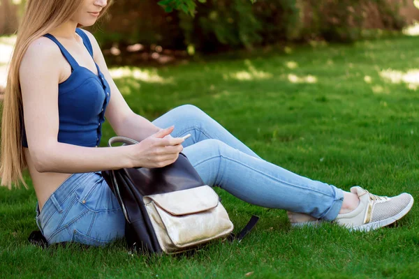 çimenlerin üzerine oturmuş ve seyir telefon bir kız