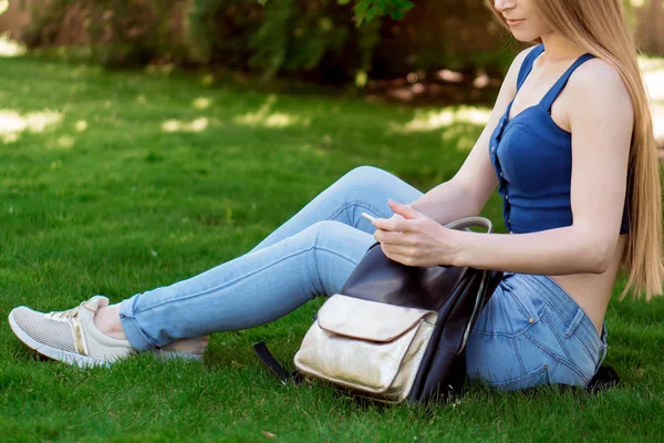 çimenlerin üzerine oturmuş ve seyir telefon bir kız