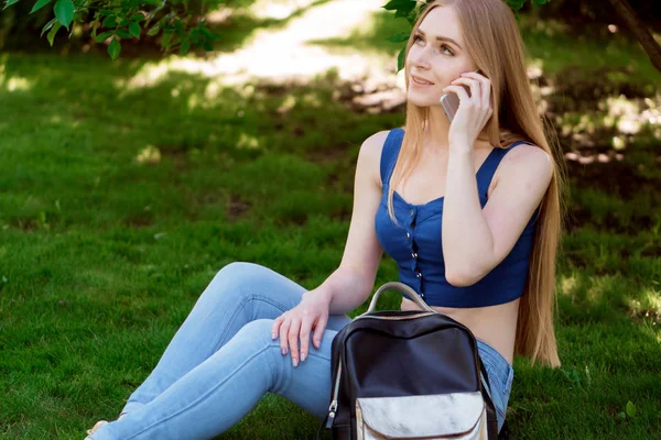 kız telefonu ve çimenlerin üzerine oturmuş