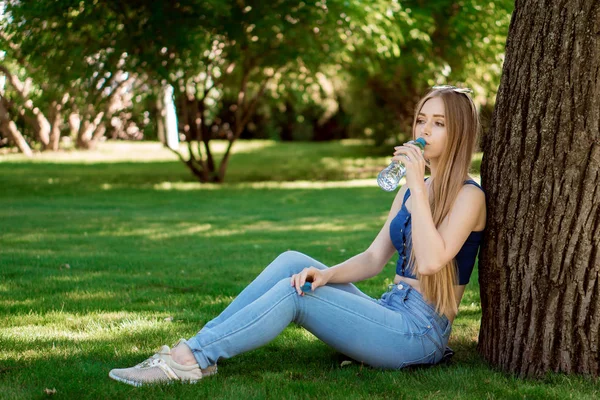 kız suyu içer ve çimenlerin üzerine oturur