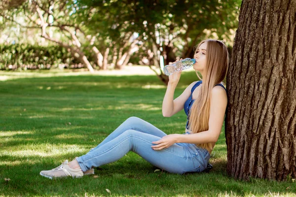 kız suyu içer ve çimenlerin üzerine oturur