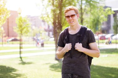 bir sırt çantası içinde bir şehir parkı ile bir adam duruyor