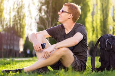 güneş ışığı altında çimlerde oturan adam