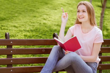  Kız parkta bir bankta oturmuş bir defter ile