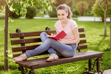  Kız parkta bir bankta oturmuş bir defter ile