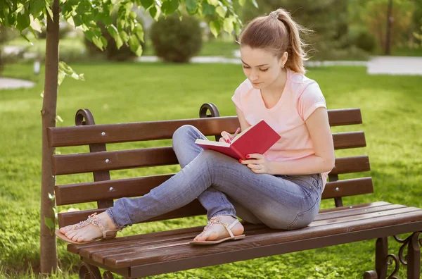  Kız parkta bir bankta oturmuş bir defter ile