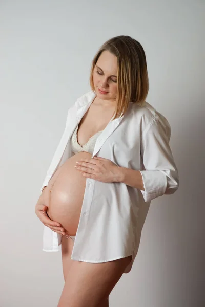 pregnant woman on white background touches belly