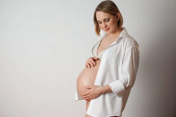 pregnant woman on white background touches belly