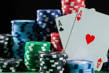 Poker fişleri iki kart ile as yığını. Siyah, koyu arka plan üzerinde yeşil masada.