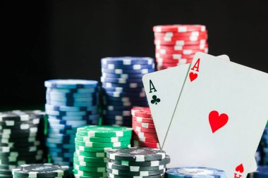 Poker fişleri iki kart ile as yığını. Siyah, koyu arka plan üzerinde yeşil masada.