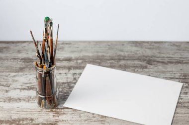 Bir cam, kavanoz, eski ahşap arka plan sonraki tuvale boya fırçası. Kopya alanı ile.