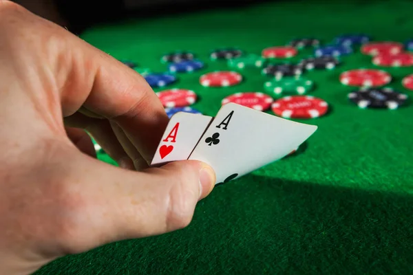 Poker chips with two aces on green background.