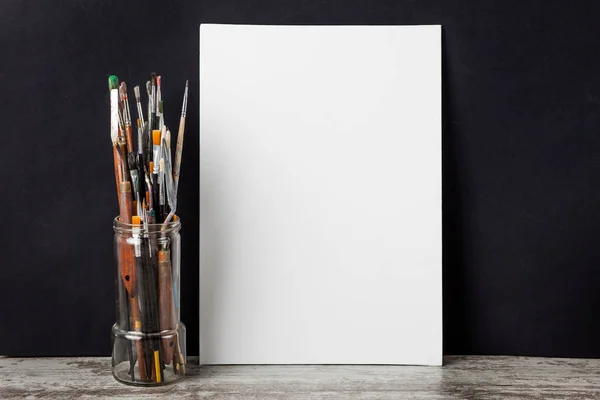 Bir cam, sonraki beyaz tuval fırça boya. siyah bir arka plan üzerinde. Kopya alanı ile.