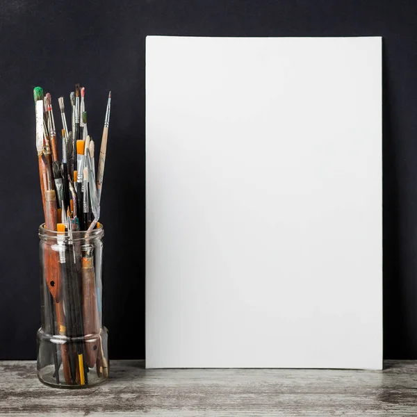 Bir cam, sonraki beyaz tuval fırça boya. siyah bir arka plan üzerinde. Kopya alanı ile.