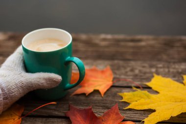 donmuş elinde kahve fincanı. arka planda sarı sonbahar yaprakları. Ahşap koyu arka plan üzerinde.