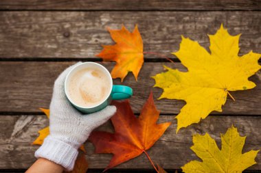 donmuş elinde kahve fincanı. arka planda sarı sonbahar yaprakları. Ahşap koyu arka plan üzerinde.