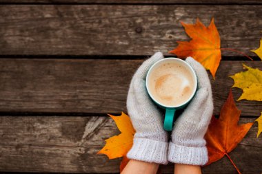 donmuş elinde kahve fincanı. arka planda sarı sonbahar yaprakları. Ahşap koyu arka plan üzerinde.