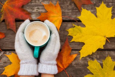 donmuş elinde kahve fincanı. arka planda sarı sonbahar yaprakları. Ahşap koyu arka plan üzerinde.