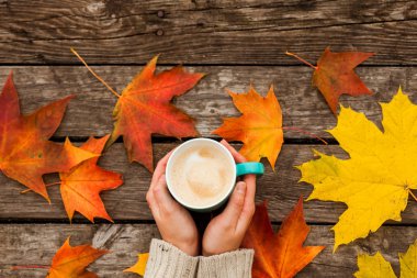 donmuş elinde kahve fincanı. arka planda sarı sonbahar yaprakları. Ahşap koyu arka plan üzerinde.