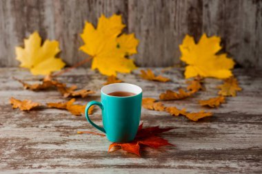 Mavi fincan çay. Ahşap eski antika arka plan. Sonbahar yaprakları. Sarı kırmızı.