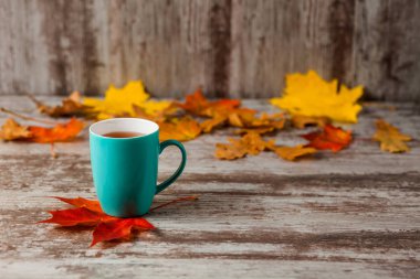 Mavi fincan çay. Ahşap eski antika arka plan. Sonbahar yaprakları. Sarı kırmızı.