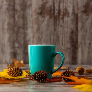 Mavi bardak çay. Sarı kırmızı yaprakları ile ahşap bir masaya. Sonbahar.