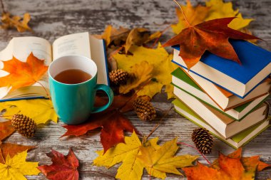 Sonbahar. Açık bir kitap. Çay, kahve, kakao. Sarı kırmızı yapraklar. Ahşap arka plan