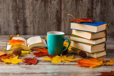 Sonbahar. Açık bir kitap. Çay, kahve, kakao. Sarı kırmızı yapraklar. Ahşap arka plan