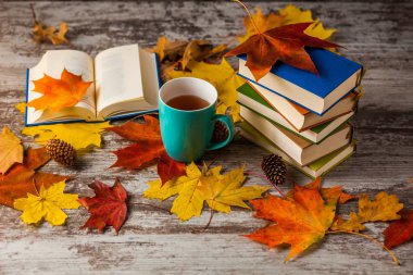 Sonbahar. Açık bir kitap. Çay, kahve, kakao. Sarı kırmızı yapraklar. Ahşap arka plan