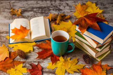 Sonbahar. Açık bir kitap. Çay, kahve, kakao. Sarı kırmızı yapraklar. Ahşap arka plan