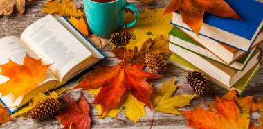 Sonbahar. Açık bir kitap. Çay, kahve, kakao. Sarı kırmızı yapraklar. Ahşap arka plan