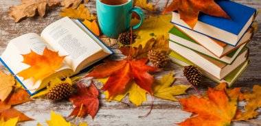 Sonbahar. Açık bir kitap. Çay, kahve, kakao. Sarı kırmızı yapraklar. Ahşap arka plan
