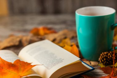 Sonbahar. Açık bir kitap. Çay, kahve, kakao. Sarı kırmızı yapraklar. Ahşap arka plan