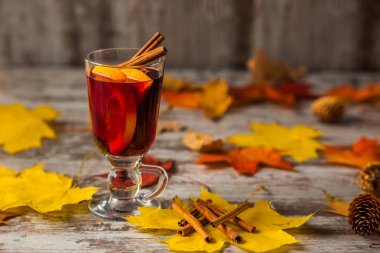 Sıcak Mulled şarap. Sonbahar arka plan üzerinde. Turuncu tarçın kırmızı şarap cam. Alkol. Sarı kırmızı yaprak. Ahşap koyu arka plan üzerinde.