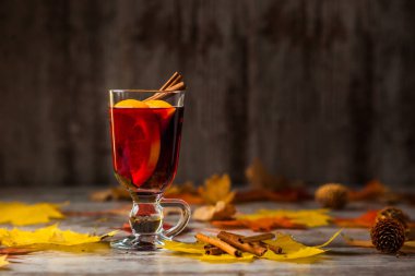 Hot Mulled Wine. On autumn background. Orange Cinnamon Red wine in the glass. Alcohol. Autumn leaves Yellow red. On wooden dark background. clipart