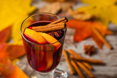 Sıcak Mulled şarap. Sonbahar arka plan üzerinde. Turuncu tarçın kırmızı şarap cam. Alkol. Sarı kırmızı yaprak. Ahşap koyu arka plan üzerinde.