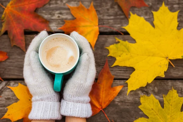 donmuş elinde kahve fincanı. arka planda sarı sonbahar yaprakları. Ahşap koyu arka plan üzerinde.