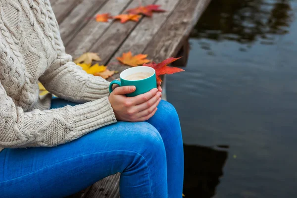 The girl froze and holding a hot Cup of coffee in hand. Autumn leaves. Blue, Red, Yellow Cold.