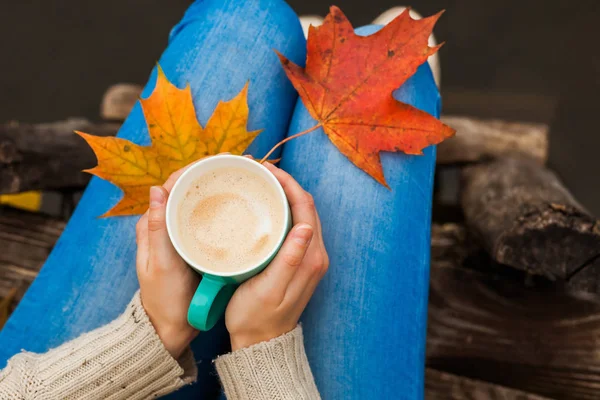 The girl froze and holding a hot Cup of coffee in hand. Autumn leaves. Blue, Red, Yellow Cold.