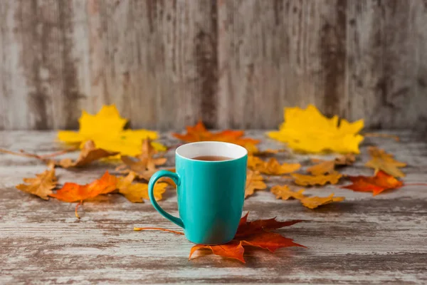 Mavi fincan çay. Ahşap eski antika arka plan. Sonbahar yaprakları. Sarı kırmızı.