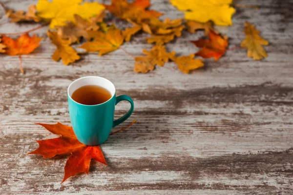Mavi fincan çay. Ahşap eski antika arka plan. Sonbahar yaprakları. Sarı kırmızı.