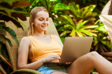 Kız bir dizüstü bilgisayarda çalışma şezlong üzerinde