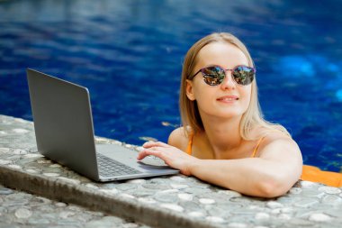 havuzun bir dizüstü bilgisayarda çalışan kız