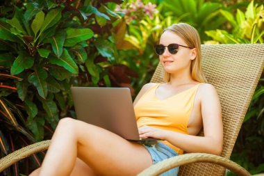 Kız bir dizüstü bilgisayarda çalışma şezlong üzerinde